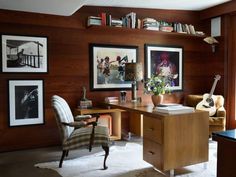 a home office with wooden walls and pictures on the wall, along with a chair