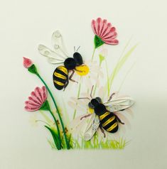 three paper flowers with two bees on them and some daisies in the grass next to each other