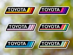 four stickers with the word toyota written in different colors and font, on a blurry background