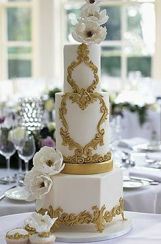 a three tiered white and gold wedding cake