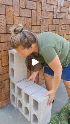 a woman placing cinder blocks into a wall