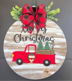 a christmas ornament with a red truck and pine trees on it's side