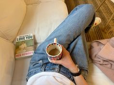 a person laying on a couch with their legs crossed holding a coffee cup