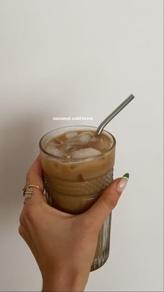 a hand holding a cup with ice and a spoon in it