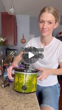 a woman standing in front of a green crock pot on top of a counter