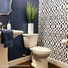 a white toilet sitting next to a sink in a bathroom under a mirror with blue walls