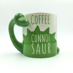 a coffee mug with a green frog on it's side and the words coffee, connoi saur written in white