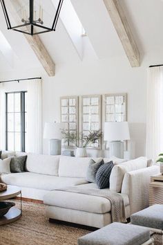 a living room filled with white furniture and lots of wood beamed ceiling beams on the walls