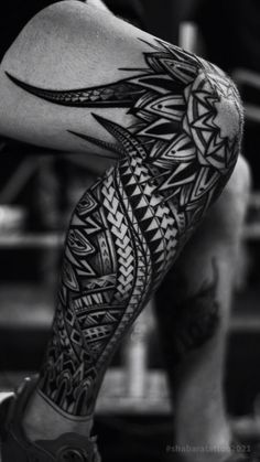 a man's leg with black and white tattoos on it