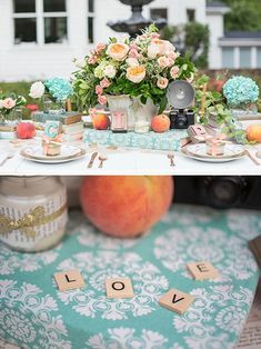 the table is decorated with peaches, flowers and scrabbles for an outdoor wedding