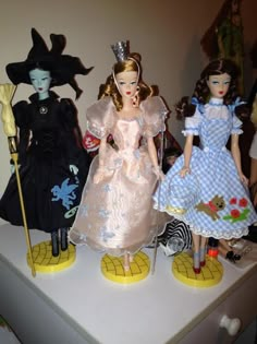 three dolls are standing next to each other on a white table with black and yellow decorations