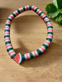 a close up of a bracelet on a table with a plant in the back ground