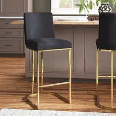 two black and gold bar stools in front of a kitchen counter with potted plant