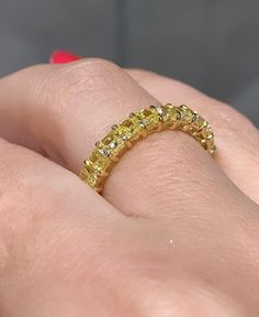 a close up of a person's hand holding a ring with yellow sapphire stones