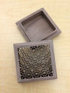 two wooden trays sitting on top of a table next to each other, one with an intricate design