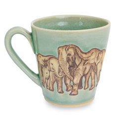 a green coffee cup with elephants painted on it