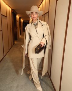 a woman in a beige suit and hat