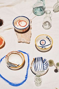 various bowls and plates are arranged on a tablecloth with blue writing in the middle