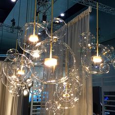 a chandelier hanging from the ceiling in a room with curtains and lights around it