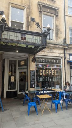 people sitting at tables in front of a coffee shop