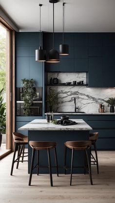 a kitchen with dark blue cabinets and marble counter tops, wooden stools, and pendant lights hanging from the ceiling