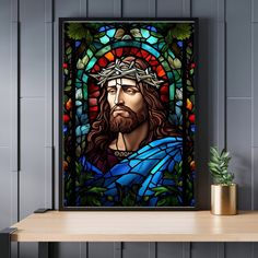 a painting of jesus in stained glass on a shelf next to a potted plant