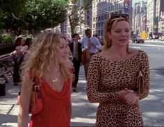 two women walking down the street talking to each other and one is wearing a leopard print dress