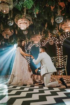 a man kneeling down next to a woman in a wedding dress on a checkered floor