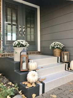 some white pumpkins are sitting on the steps in front of a house with flowers