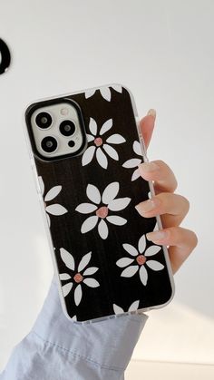 a woman holding up her phone case with flowers on it