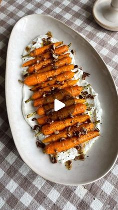 a white plate topped with carrots covered in whipped cream and chocolate sauce on top of a checkered table cloth