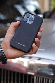 a hand holding an iphone in front of a car