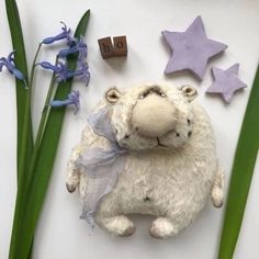 a stuffed animal laying next to some purple flowers and star shaped magnets on a white surface