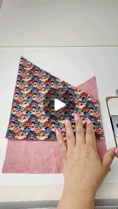 a woman is working on a piece of fabric with scissors and sewing machine in the background