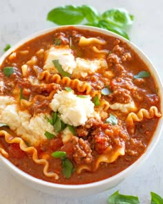 a white bowl filled with pasta and meat sauce on top of a marble countertop