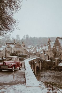 an old red car parked on the side of a road in front of some houses