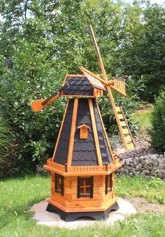 a small wooden windmill sitting in the grass