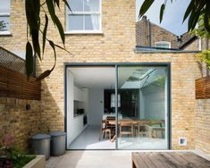 an open patio area with wooden benches and tables in front of a brick building that has glass doors leading to the outside