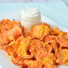 a white plate topped with potato chips and a small jar of whipped cream next to it