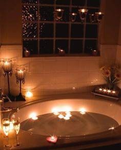 candles are lit in the bathtub as it sits next to a window