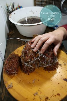 someone is cutting up some kind of wire on a wooden board with a bowl in the background