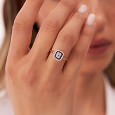 a woman holding her hand up to her face with a diamond ring on it's finger