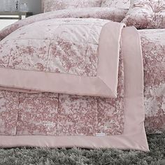 the comforter is made up with pink and white floral designs on it's bed