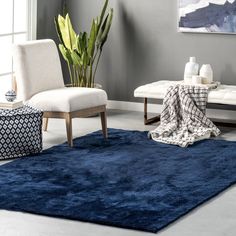 a living room with blue rugs and white furniture in the corner, along with a large painting on the wall