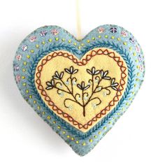 a heart shaped ornament hanging from a string on a white background with flowers and leaves