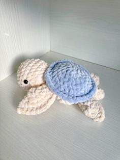 a crocheted turtle sitting on top of a white table next to a wall