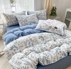 a bed with blue and white comforters in a living room next to a window