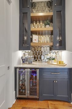 a kitchen with gray cabinets and stainless steel appliances in the corner, along with wooden flooring