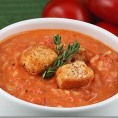 a white bowl filled with tomato soup and two croutons on top of it