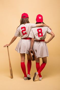 two women in baseball uniforms are hugging each other with their arms around one another while holding a baseball bat